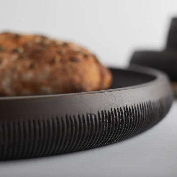 Close-up of a black tray with a blurred food item inside on a light background