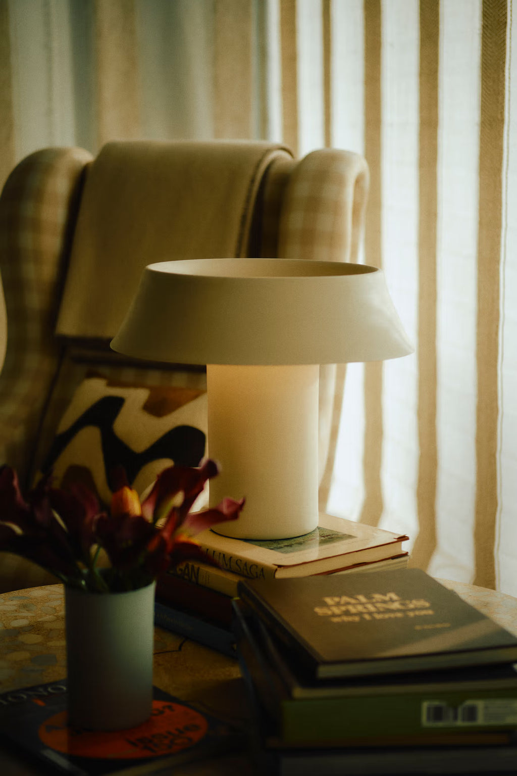 Lamp on a table with books and decorative items in a cozy room setting.