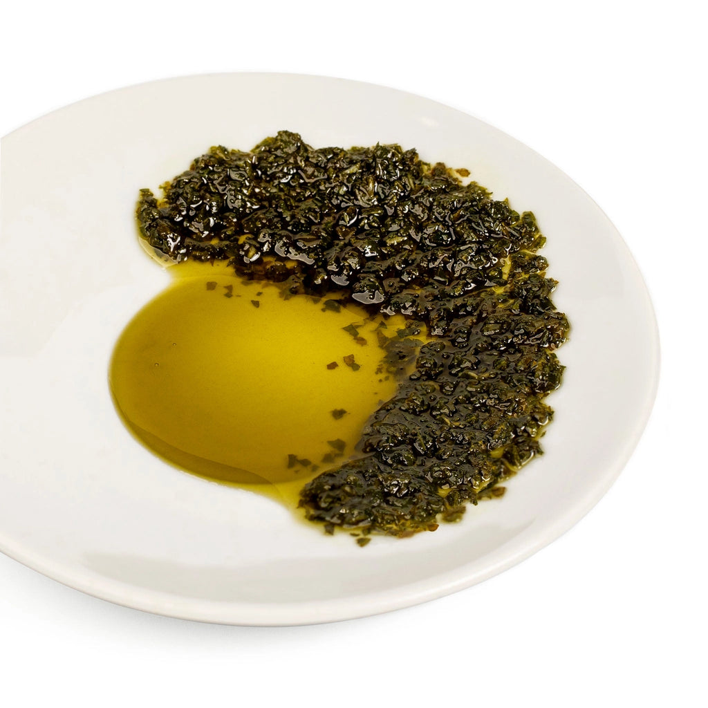 Green leafy substance on a white plate with a yellow liquid.