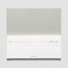 A single-page sticky note pad with a textured light gray cover and a white lined writing page showing columns for task, priority, and done, on a light gray background.