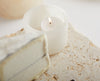White candle in a holder on a marble surface