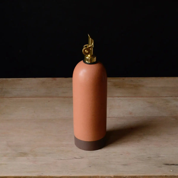 Pink ceramic bottle with gold cap on a wooden surface