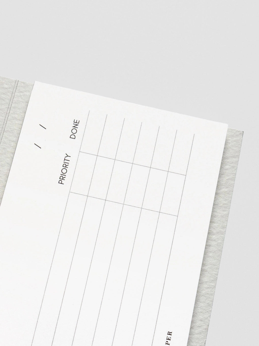 White planner sheet with grid layout on a gray surface