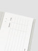 White planner sheet with grid layout on a gray surface