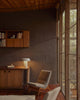 Modern interior with wooden furniture, bookshelf, white lamp and chair near a large window.