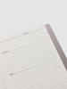 Close-up of a planner with sections for schedule, priorities, and tasks on a white background.