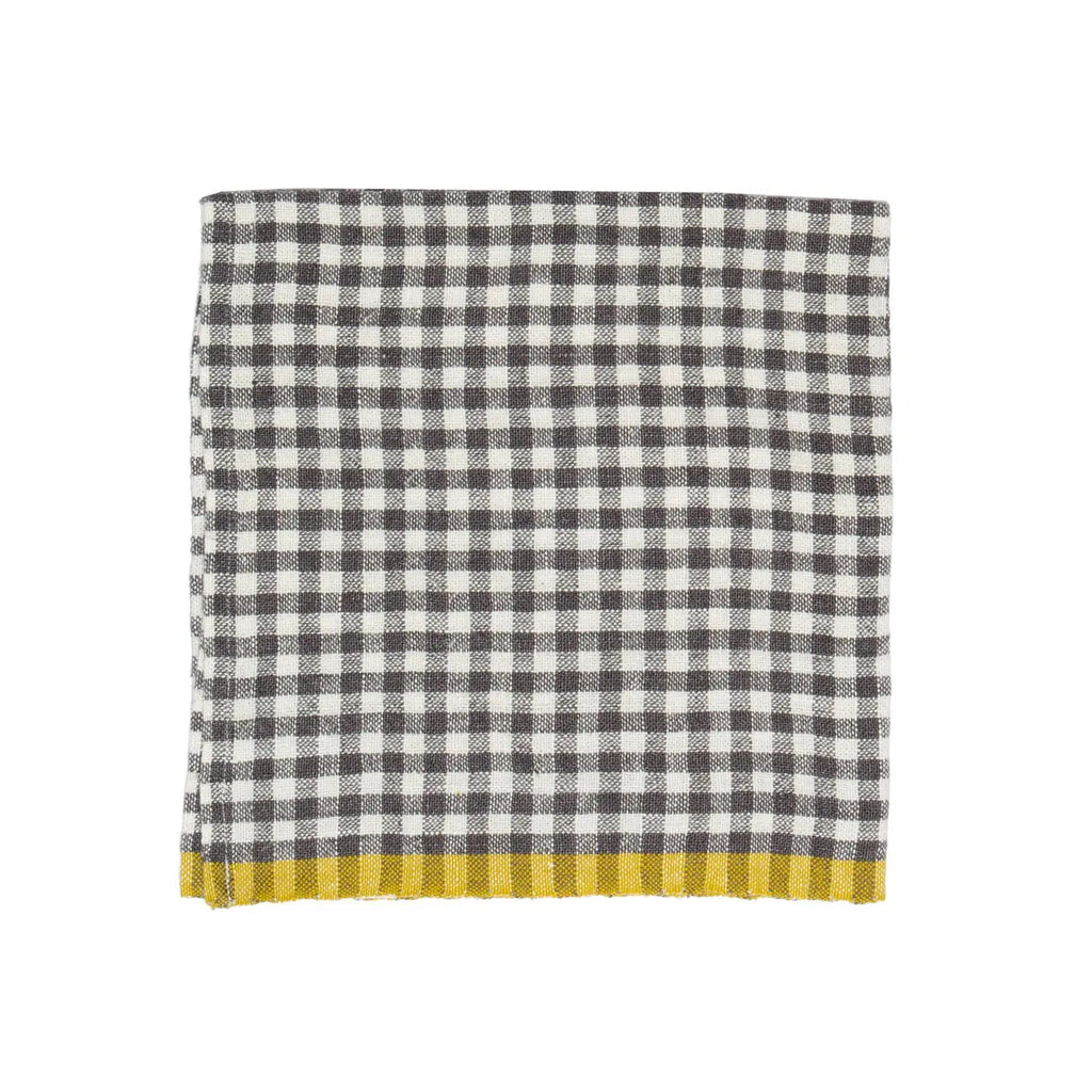 A folded checkered napkin with a black and white gingham pattern and a solid mustard yellow fringed border, shown on a plain white background.