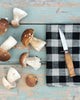 Mushrooms and a knife on a checkered cloth with a rustic wooden surface