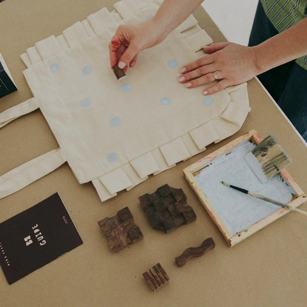 Person working with tote bag and printing blocks on a table