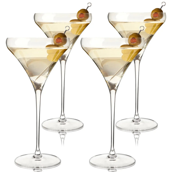 Four clear martini glasses filled with a pale yellow drink and garnished with olives on a white background.