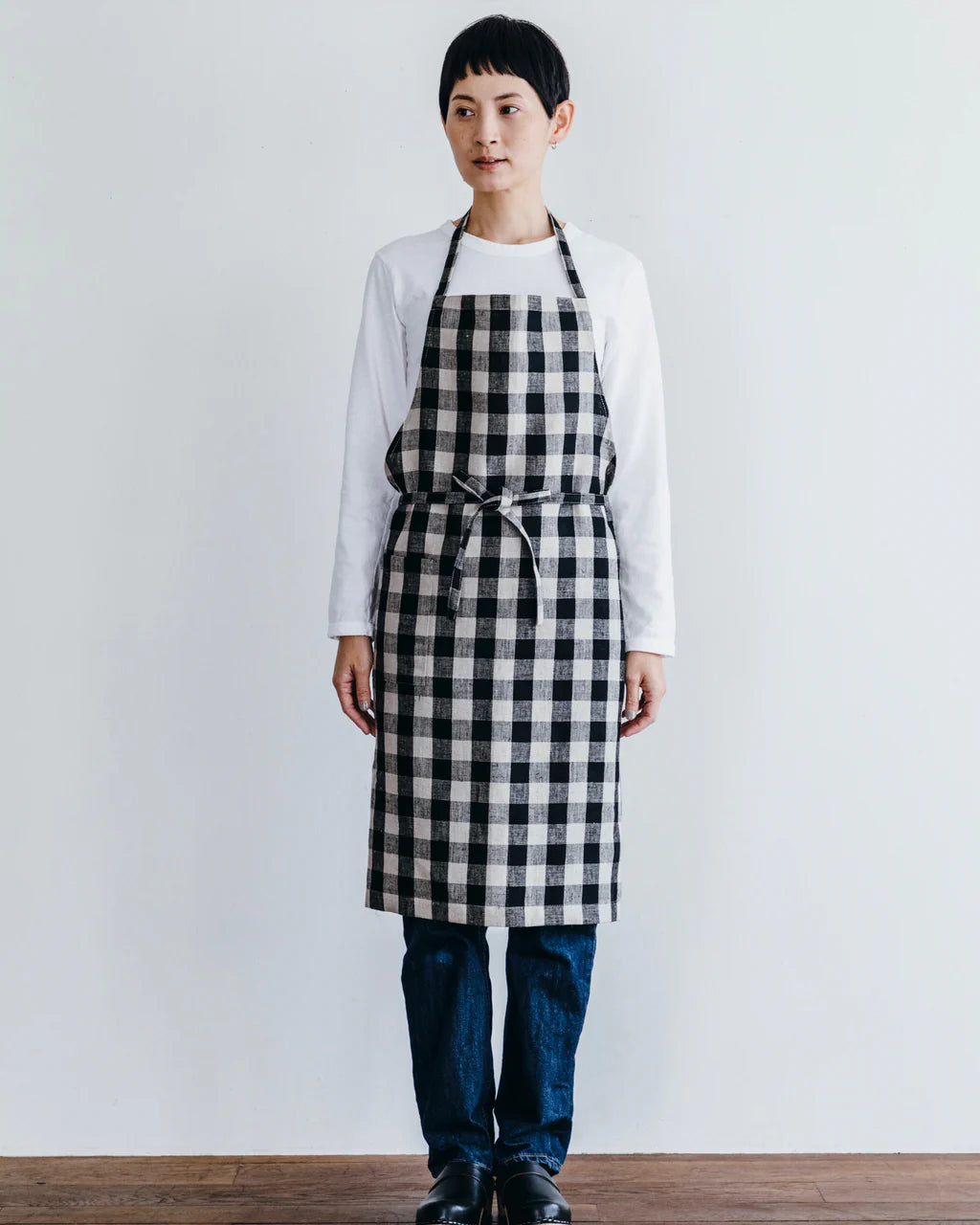 Person wearing a black and white checkered apron against a plain background