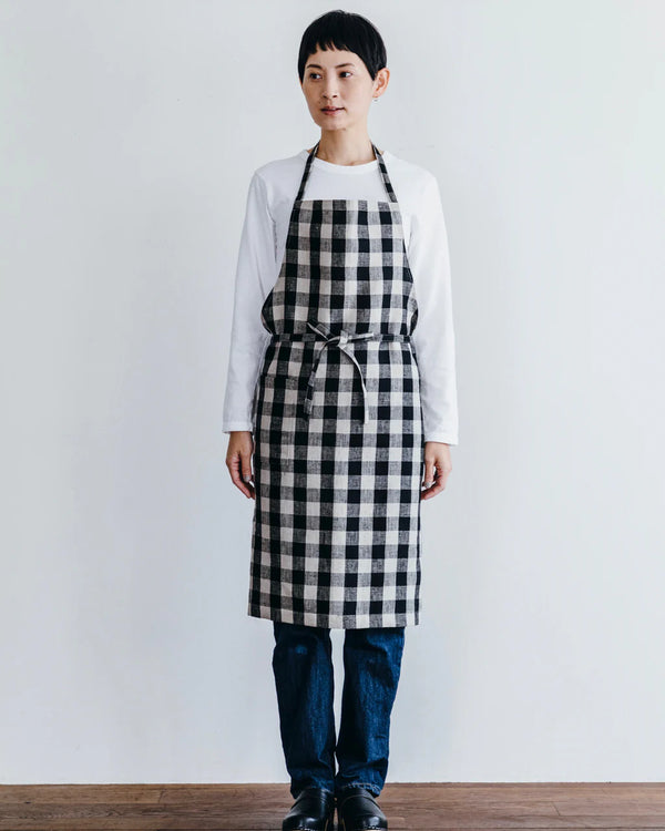 Person wearing a black and white checkered apron against a plain background