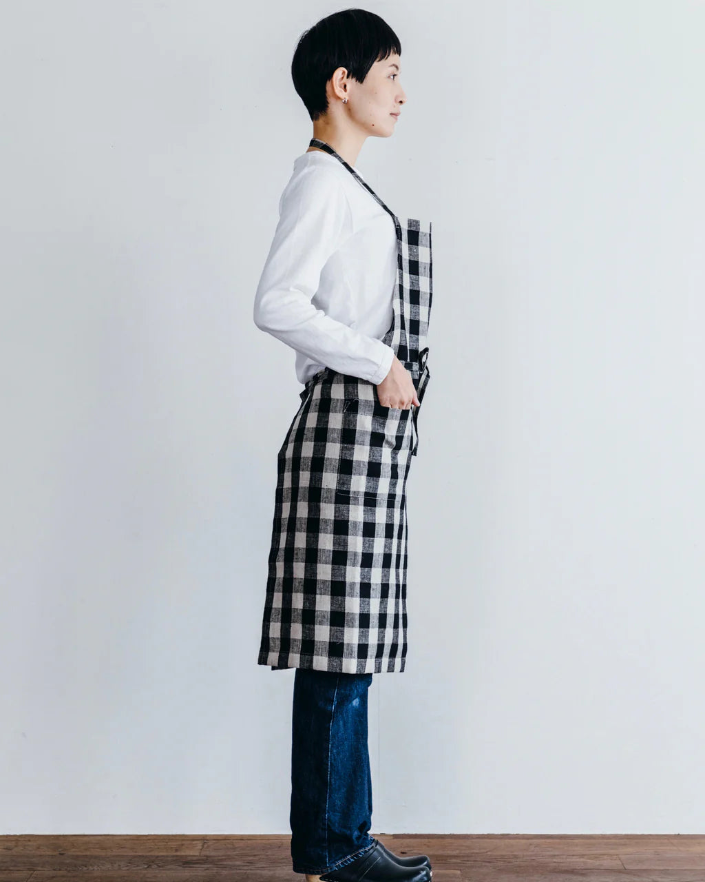 Person wearing a black and white checkered apron against a plain background