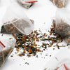 Tea bags with loose tea leaves on a white surface