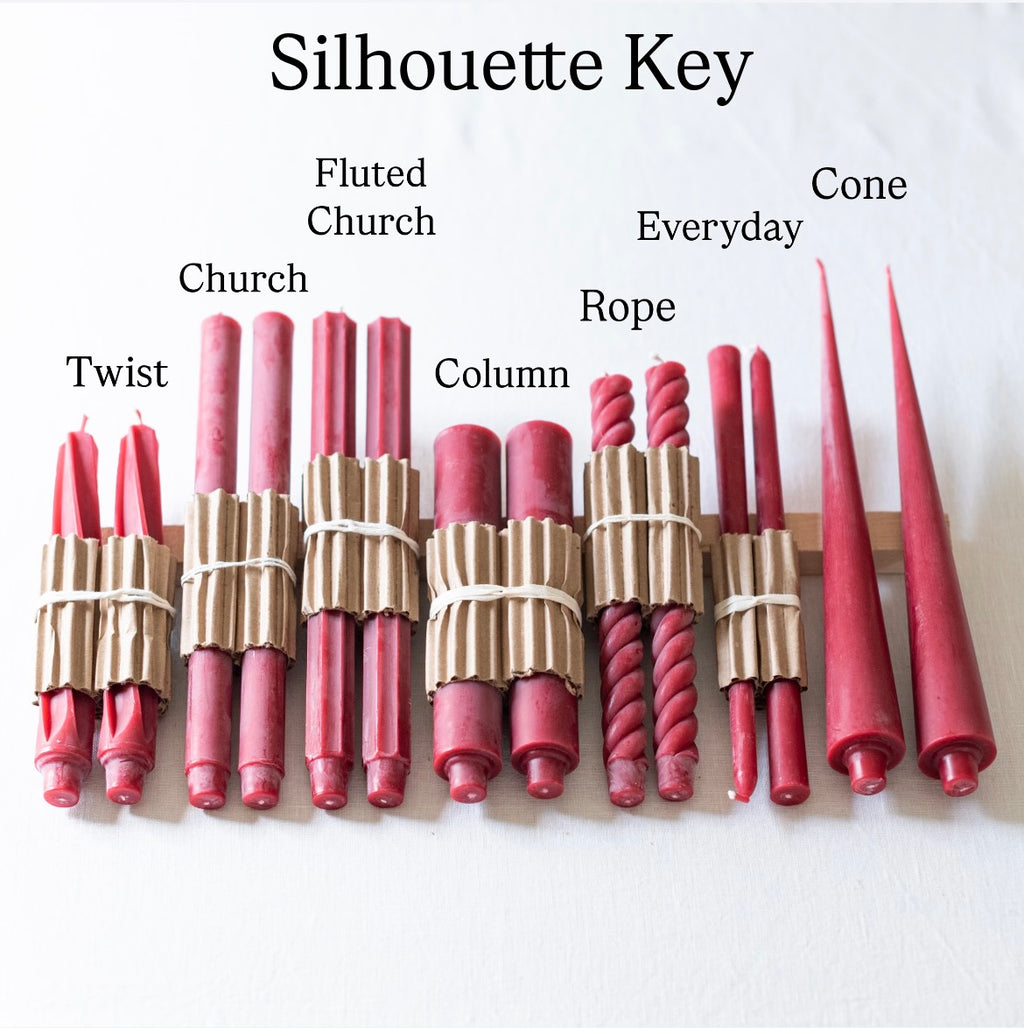 A selection of red taper candles arranged by design, with natural and twisted patterns, made from beeswax, displayed to help decide on silhouette.