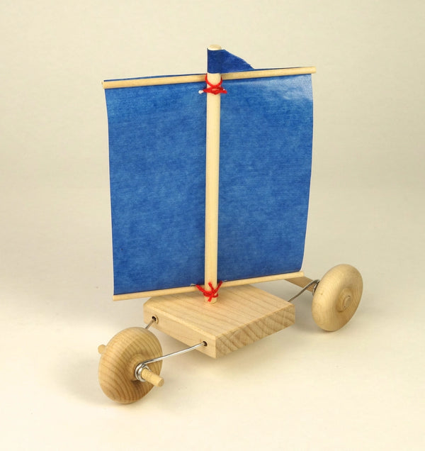 Wooden toy sailboat with a blue sail on a beige background