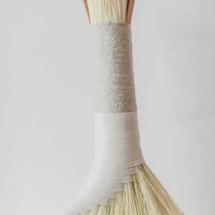 Tampico broom with a woven handle on a light gray background