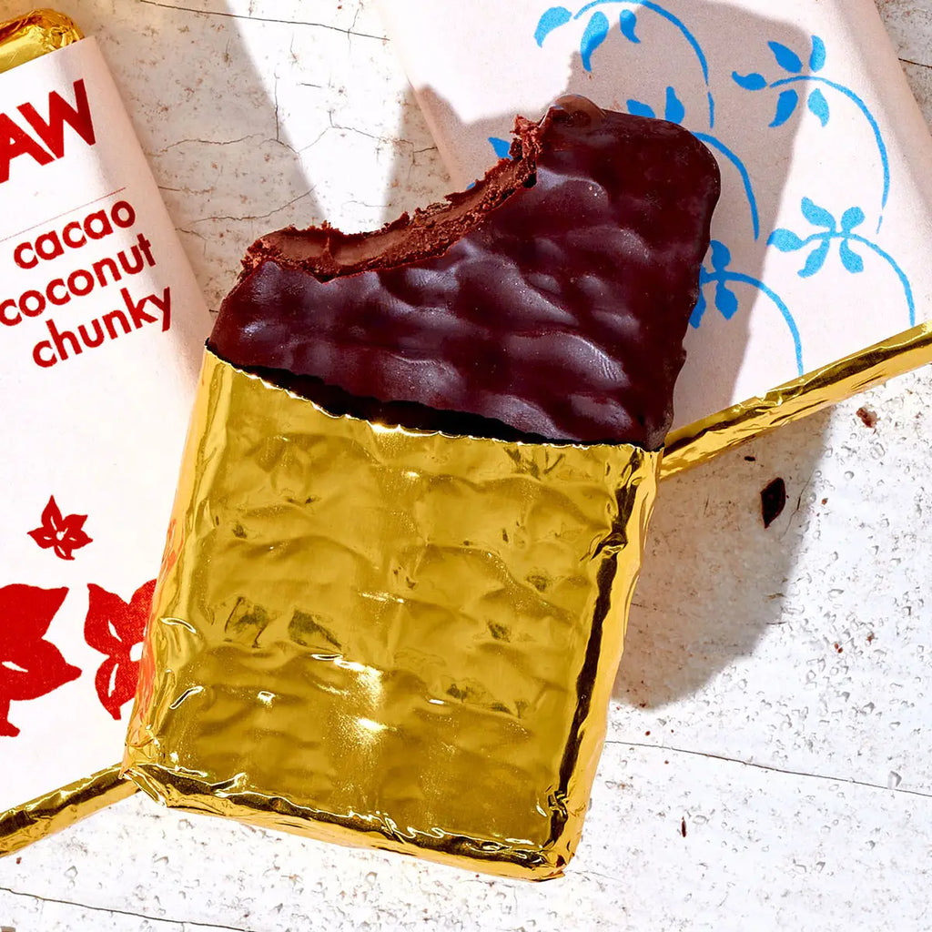 Chocolate bar with gold foil wrapper on a white surface with a floral patterned paper.