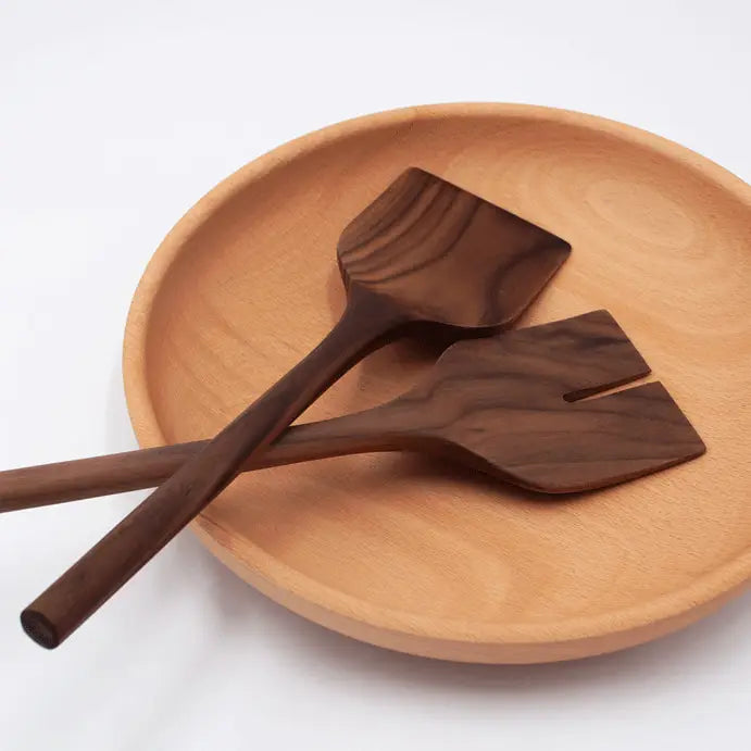 Wooden salad spoons on a wooden plate with a white background