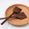 Wooden salad spoons on a wooden plate with a white background