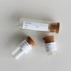 Three small glass vials with cork stoppers on a light gray background