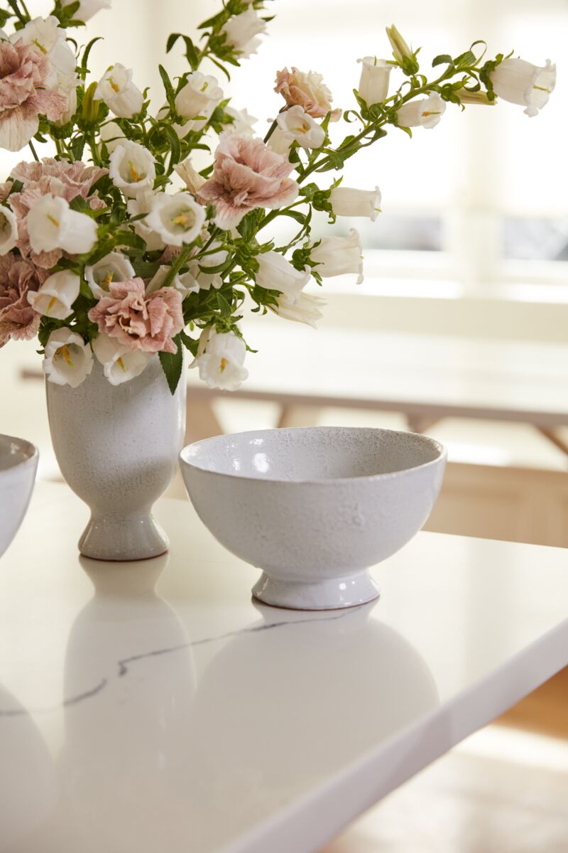 White vase with pink and white flowers on a marble surface