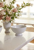 White vase with pink and white flowers on a marble surface