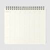 A weekly schedule planner page from an open spiral-bound notebook, showing a grid layout for Monday through Sunday with columns for days and blank spaces on the left, photographed on a light gray background.