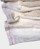 Close-up of a white fabric with red stitching on a light gray background