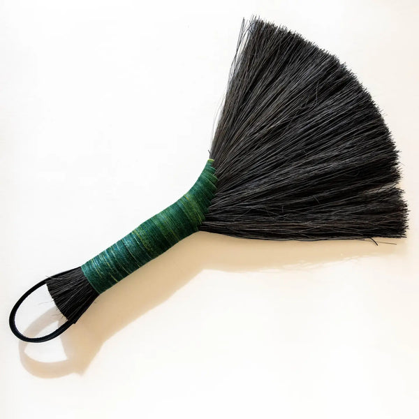 Duster with black bristles and a green handle on a white background