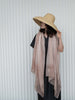 Person wearing a wide-brimmed hat and light pink scarf against a white background