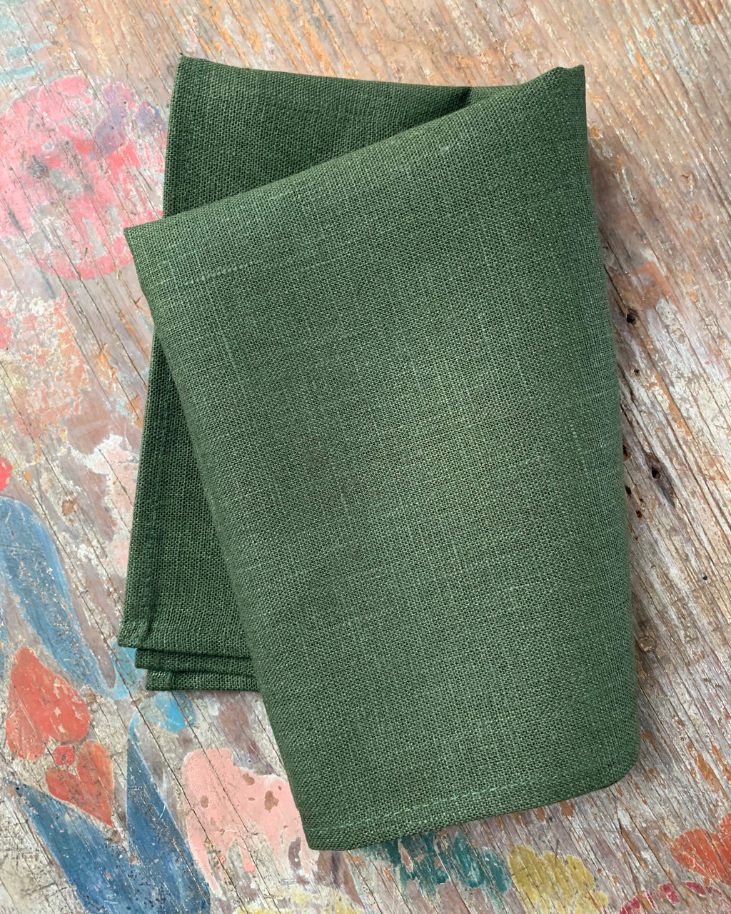 Folded green fabric on a textured wooden surface