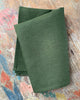 Folded green fabric on a textured wooden surface