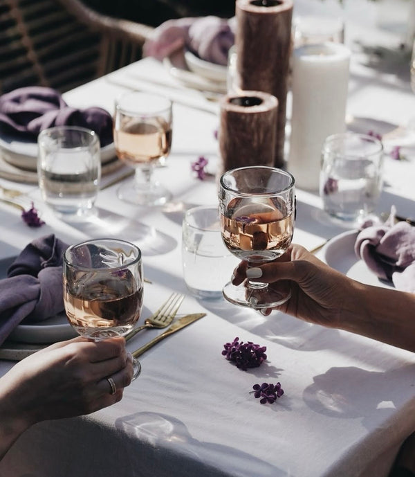 Two people toasting with glasses of wine at a dinner table.