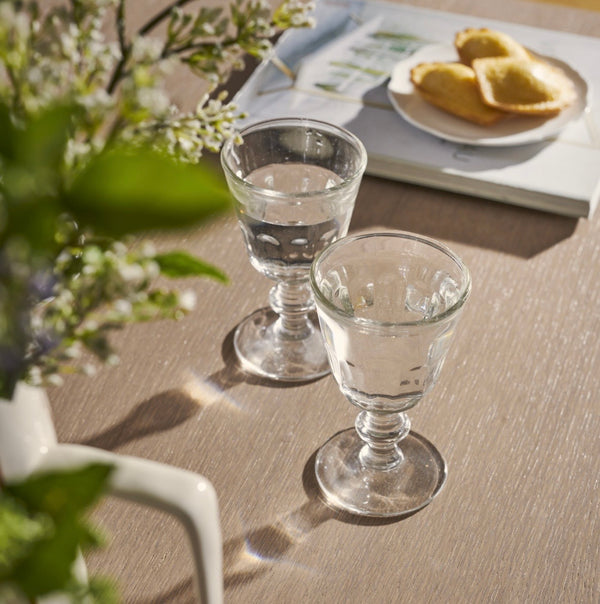 Two clear glasses on a wooden table with a blurred background