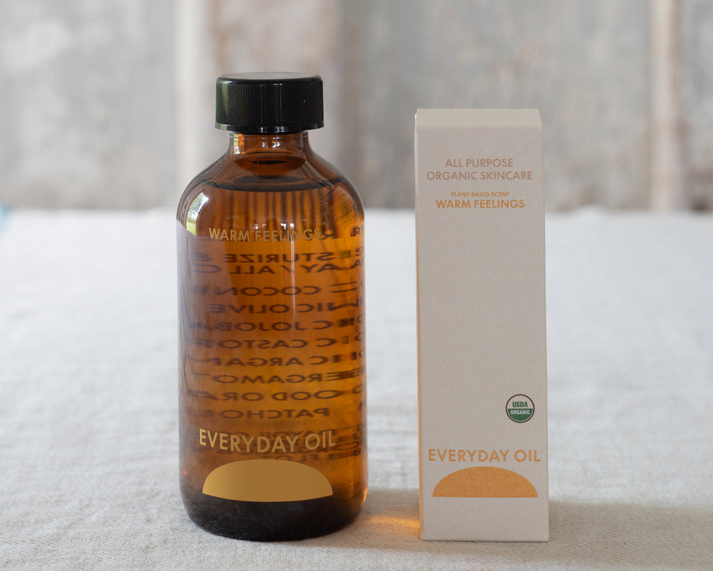 Bottle and box of Everyday Oil on a textured surface with a blurred background