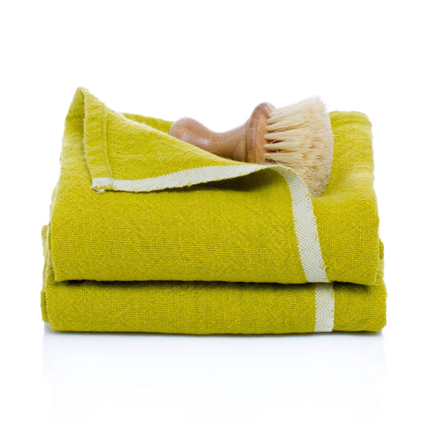 Folded green towel with a scrub brush on a white background