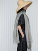 Person wearing a straw hat and gray scarf against a white background