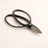 Black scissors with a silver blade on a white background