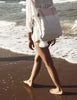 Person walking on a beach with a colorful bag