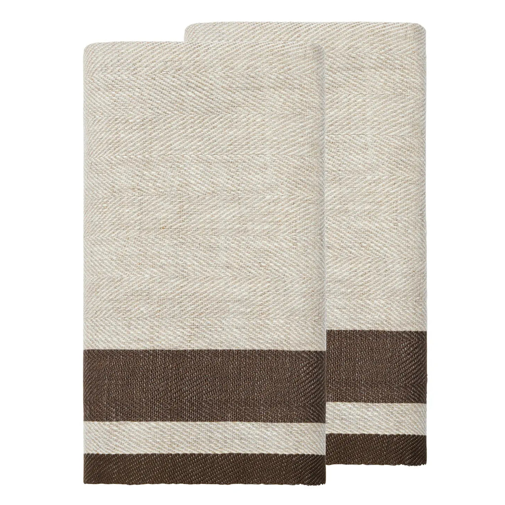 Two folded woven towels in a light beige and white herringbone pattern with a contrasting dark brown stripe near the bottom, displayed on a solid white background.
