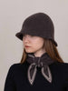 Woman wearing a dark brown cloche hat and matching scarf against a plain background