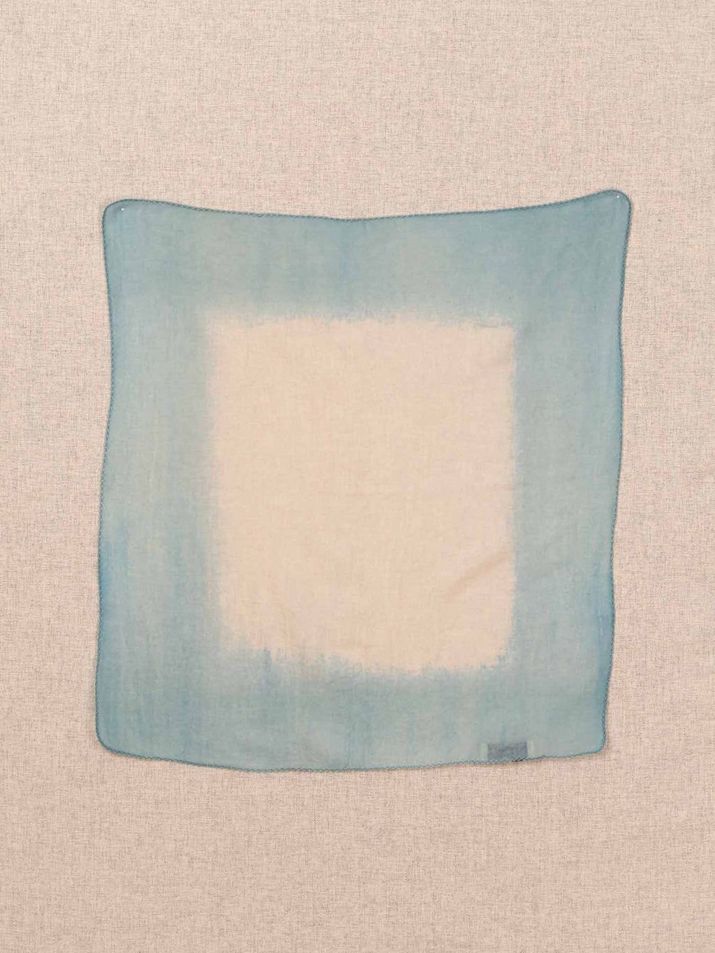 Blue and white square fabric swatch on a beige background