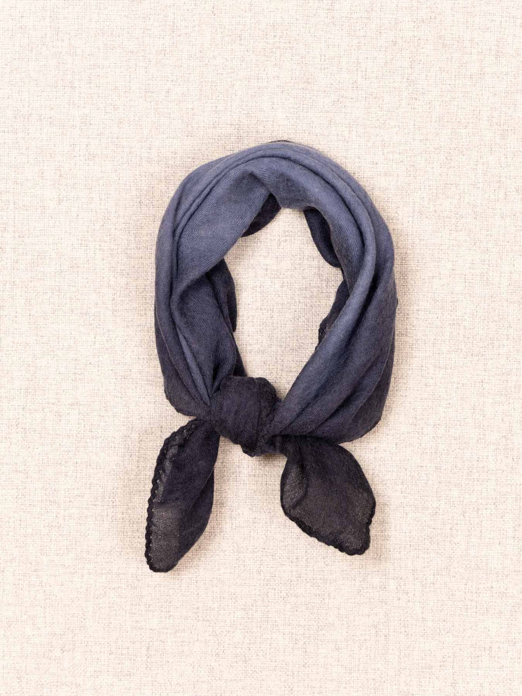 Navy blue scarf tied into a knot on a beige background