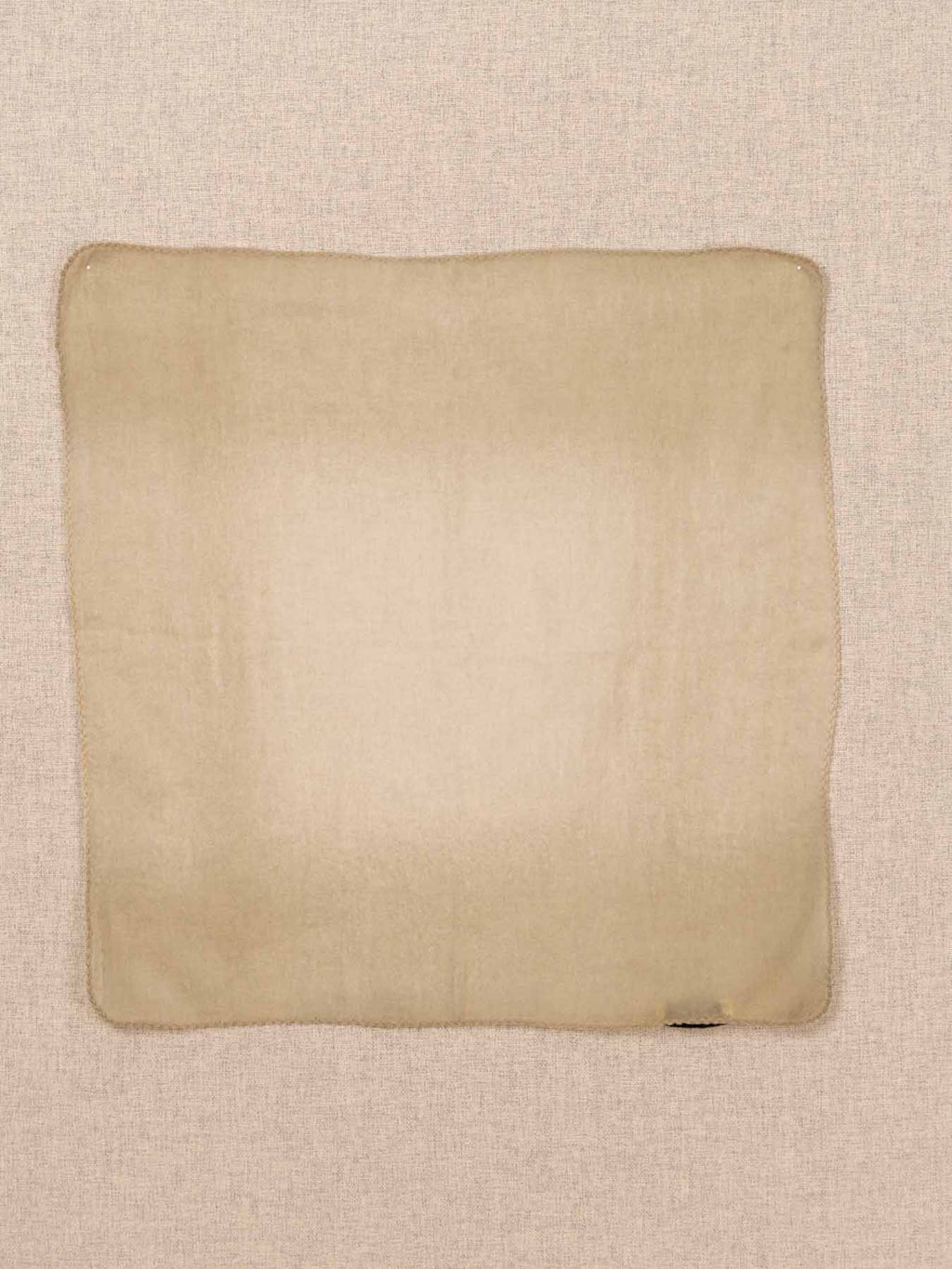 A square scard made of a soft cashmere, laid flat against a textured beige linen background.