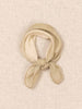 A beige knotted scarf made of soft cashmere fabric, displayed on a textured beige linen-like background.