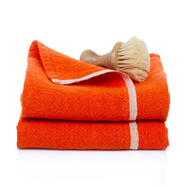 Stack of orange towels with a wooden brush on a white background