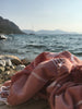 Pink towel with white stripes on a wooden surface by the sea