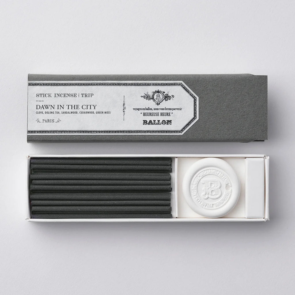Incense sticks and a round incense burner in a gray box on a light gray background
