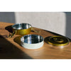Two metal bowls, one white and one gold, on a wooden surface with a neutral background.